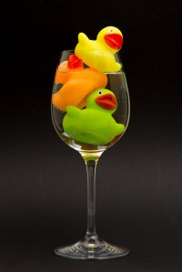 Yellow, orange and green rubber duck in a wineglass