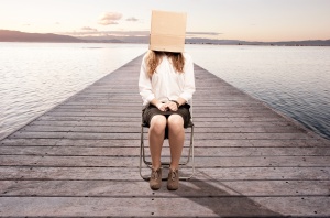 woman sitting on a wharf with a box in her face