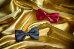 Red and black bow ties on draped golden satin