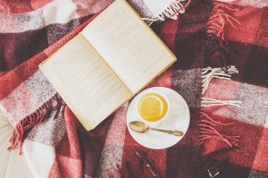 Cup of hot tea and reading on a blanket, instagram style toned. Top view point.