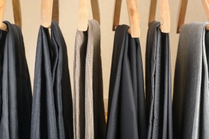 Different types of pants on wooden hangers. Selective focus.